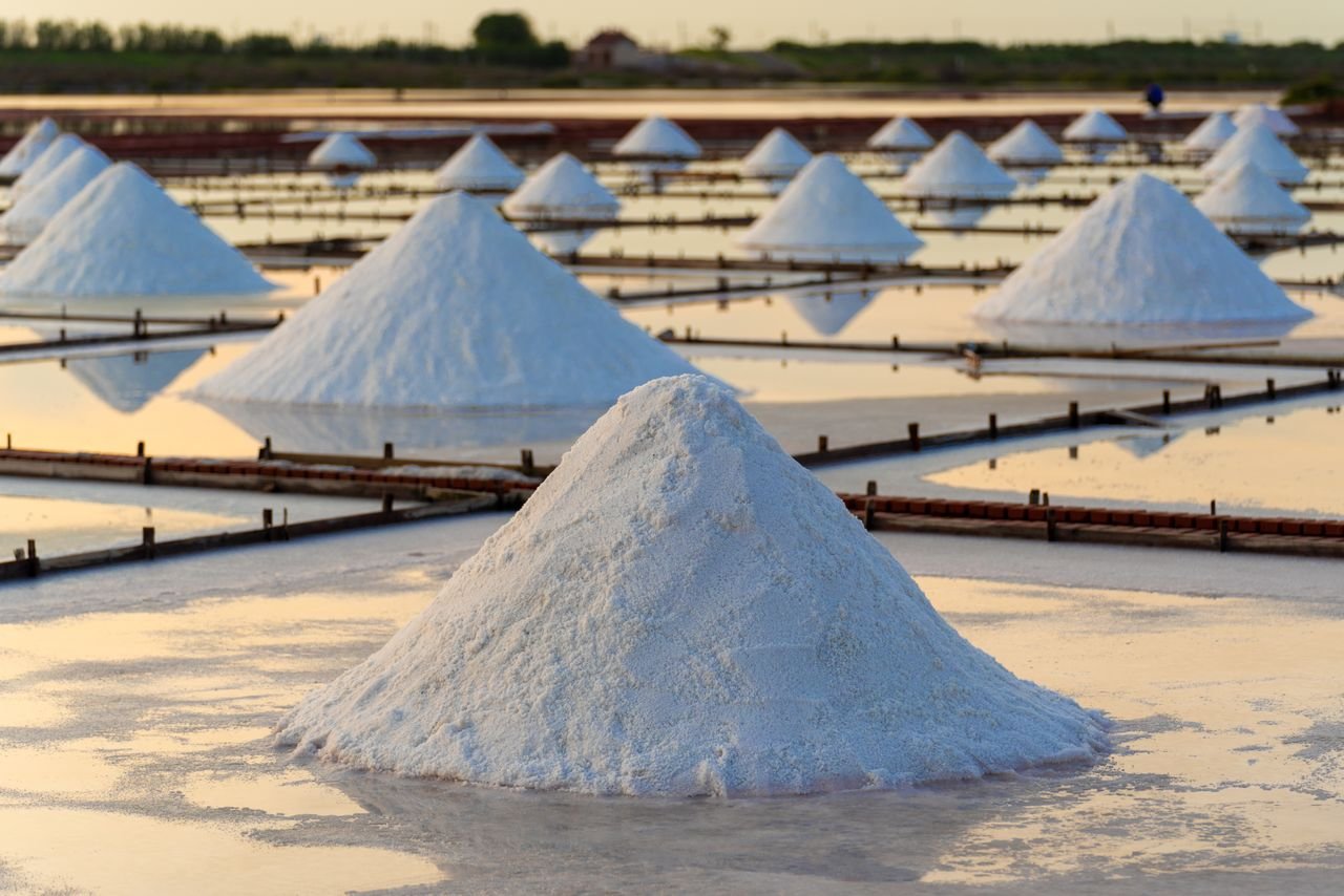 Scenic view of salt piles reflecting sunlight on Tainans salt flats, capturing traditional salt production process.